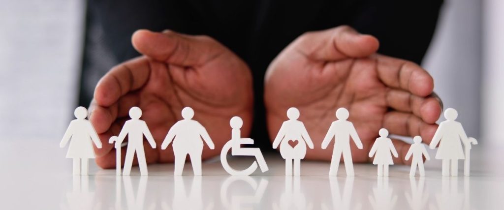 Manos protegiendo figuras de personas diversas, entre ellas una persona en silla de ruedas, personas mayores y niños